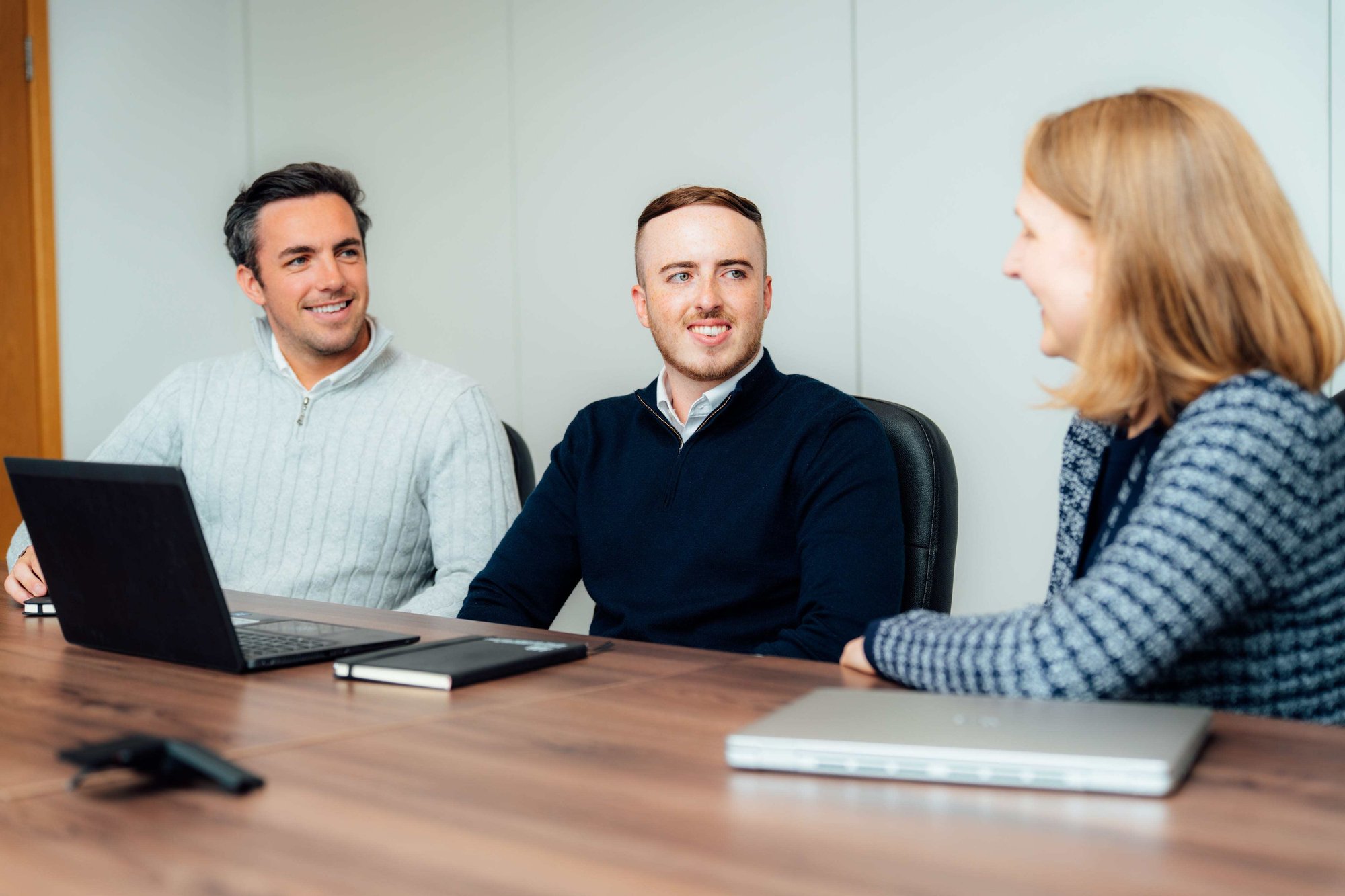 An image of 3 AAB employees in a conversation whilst sitting at their desk.