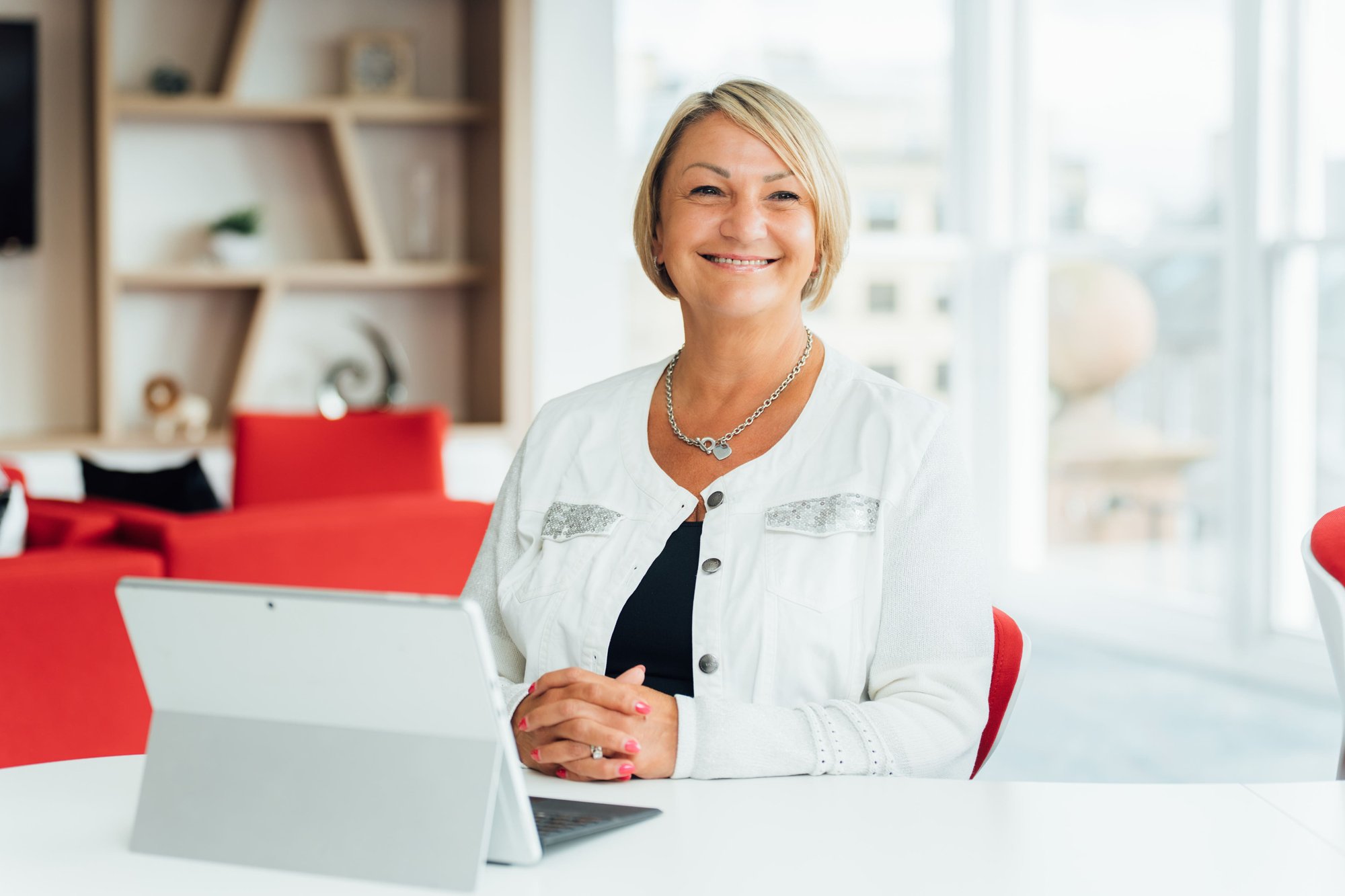 An image of Myra Bartlett wearing a white jacket and smiling at the camera in the office.